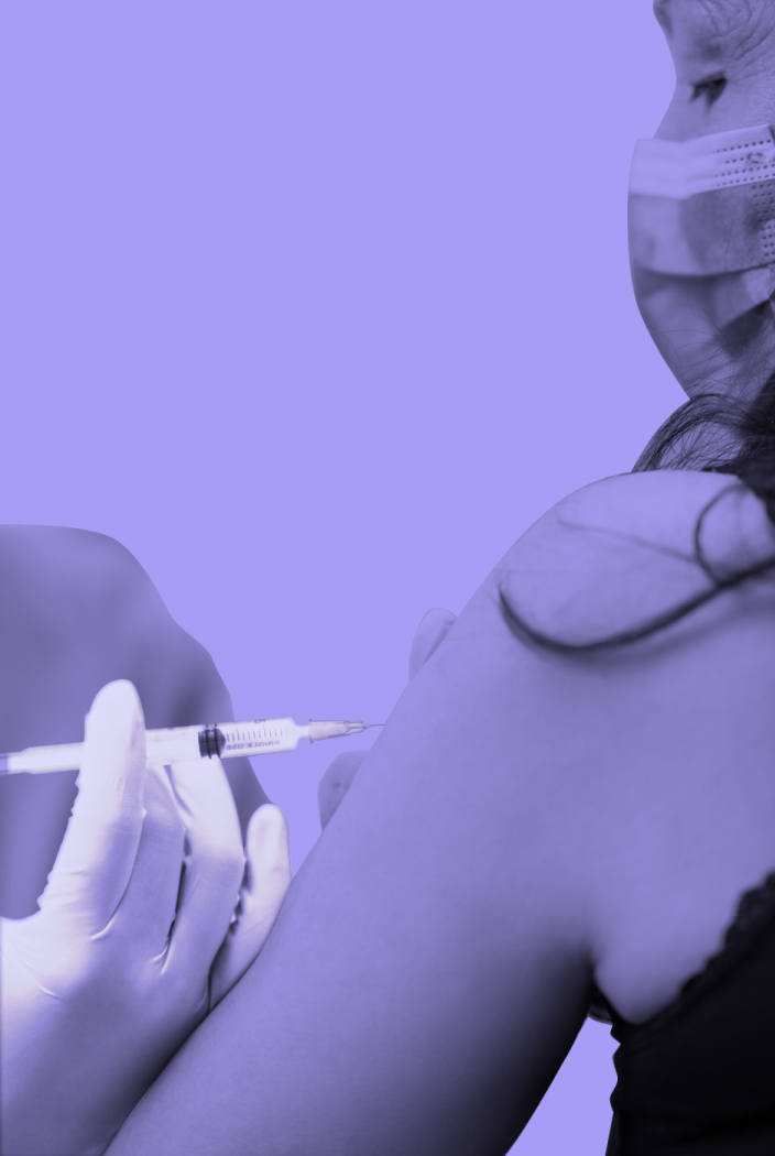 A person wearing a surgical mask receives a vaccine shot in their arm