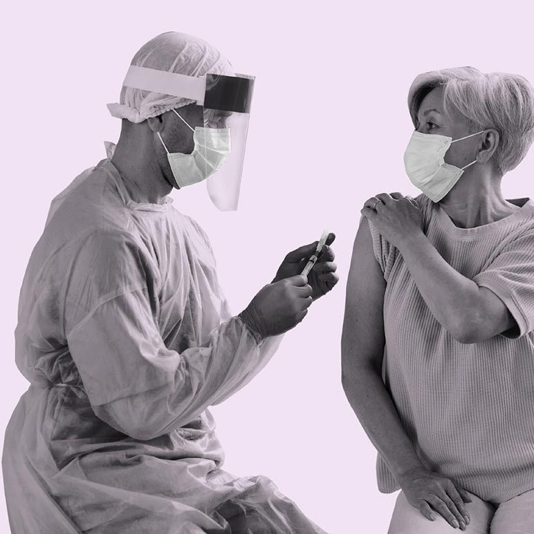 Une personne se faisant vacciner par un travailleur de la santé portant tous les deux des masques chirurgicaux