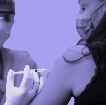 A person wearing a surgical mask receives a vaccine shot in their arm